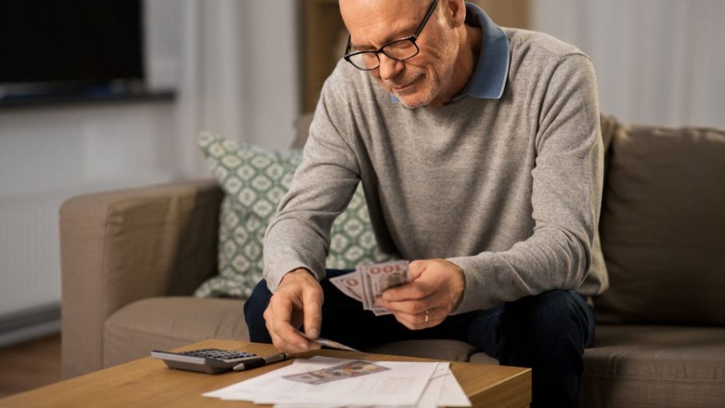 middle aged man counting cash on his couch