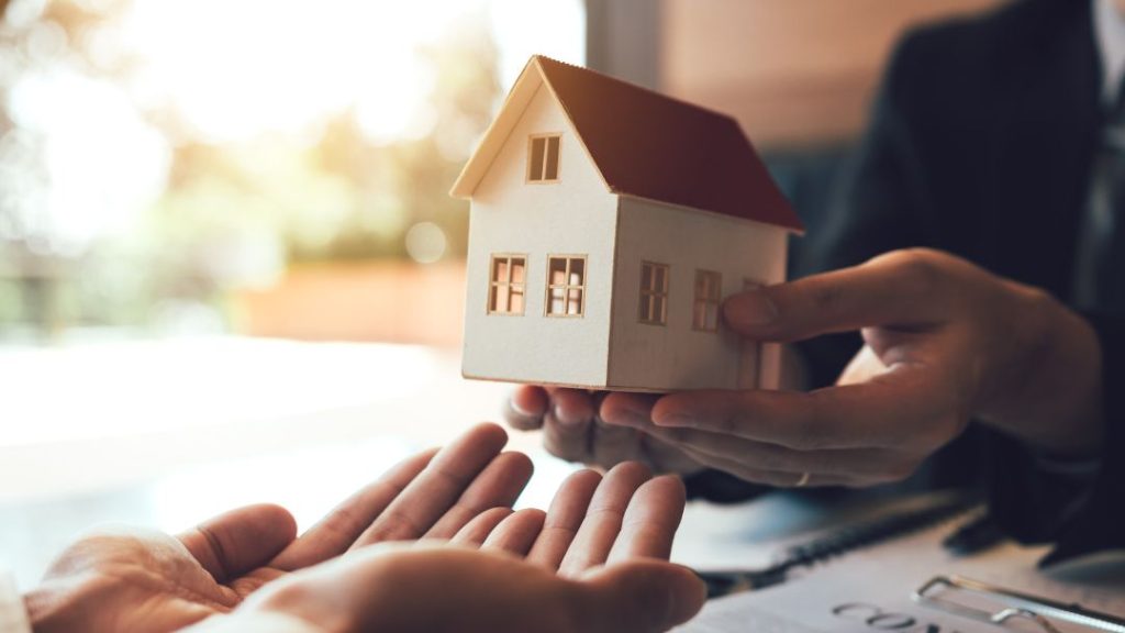 person handing over small model house