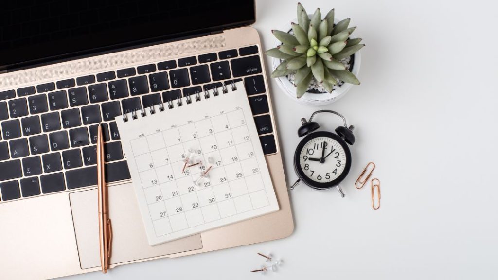 calendar, clock, pen, and push pins on laptop